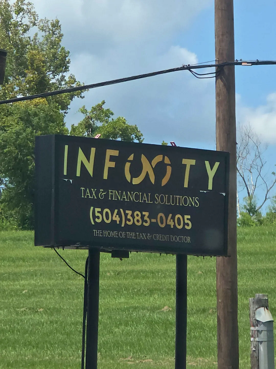 A roadside sign reads "INFINITY TAX & FINANCIAL SOLUTIONS" with a stylized infinity symbol. Below is the phone number (504) 383-0405 and the tagline "The Home of the Tax & Credit Doctor." Grass and trees are in the background.