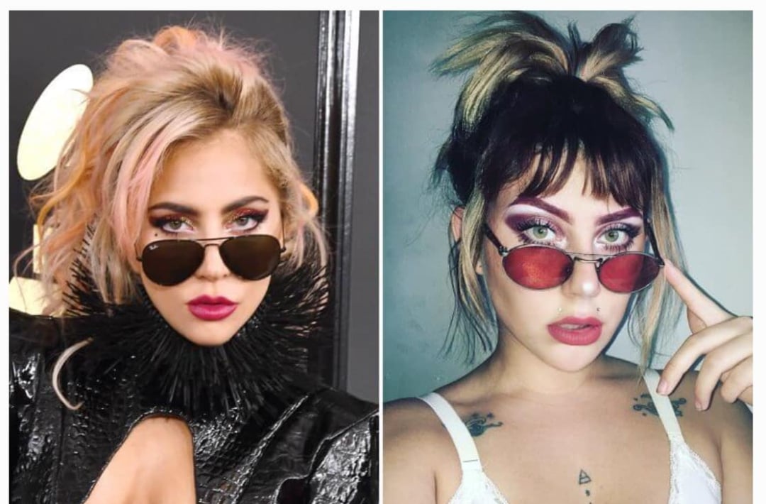 Two women with striking makeup and similar hairstyles wear tinted sunglasses. The woman on the left has blonde and pink hair in an updo and a dramatic black outfit, while the woman on the right has brown hair in a messy ponytail and casual attire.