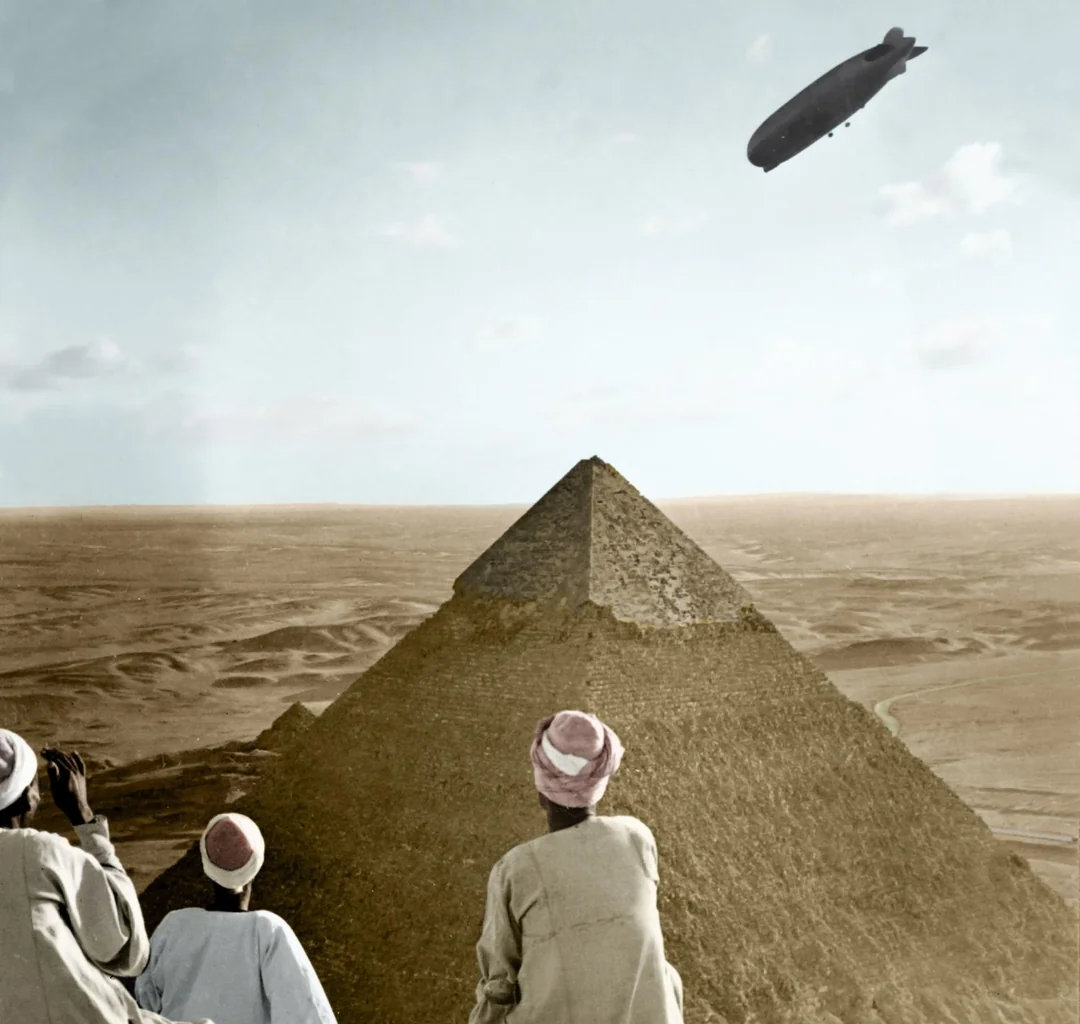 Three people in traditional clothing look at the Great Pyramid of Giza while a large airship or zeppelin floats in the sky above the pyramid, set in a vast desert landscape.