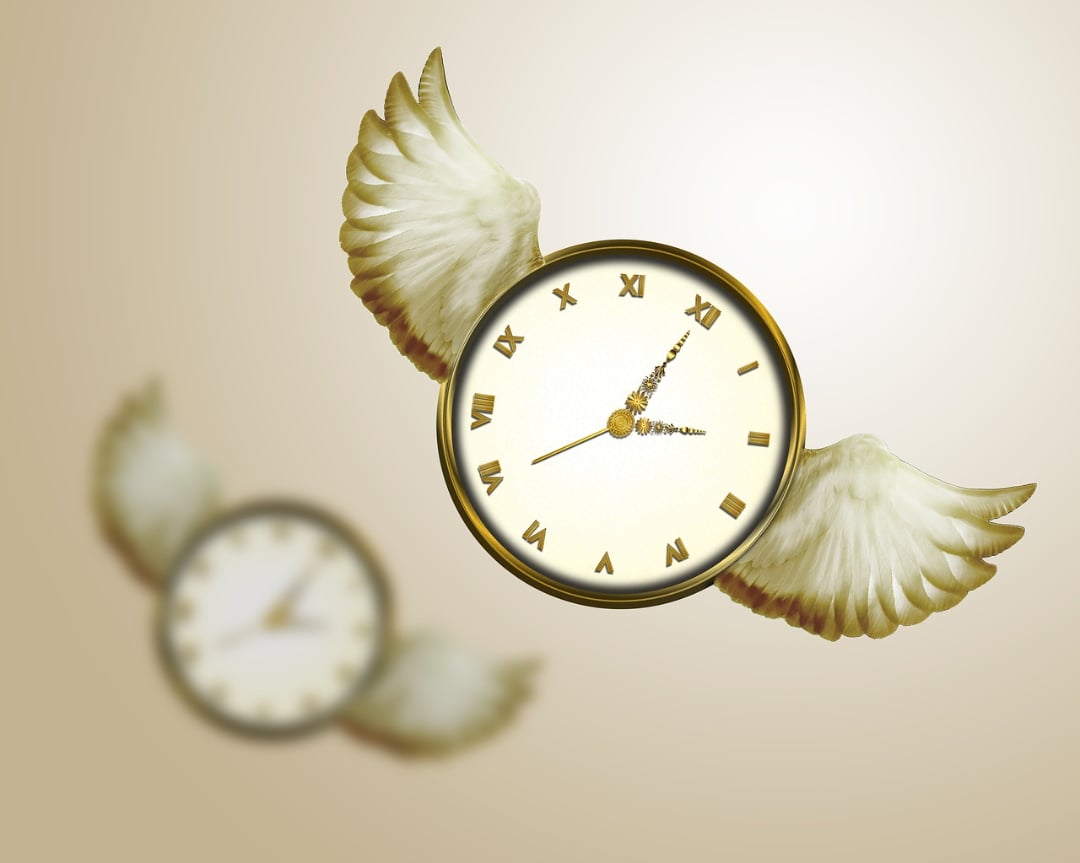 A clock with Roman numerals and golden wings appears to be flying, with another blurred clock with wings in the background, symbolizing the concept of "time flies.