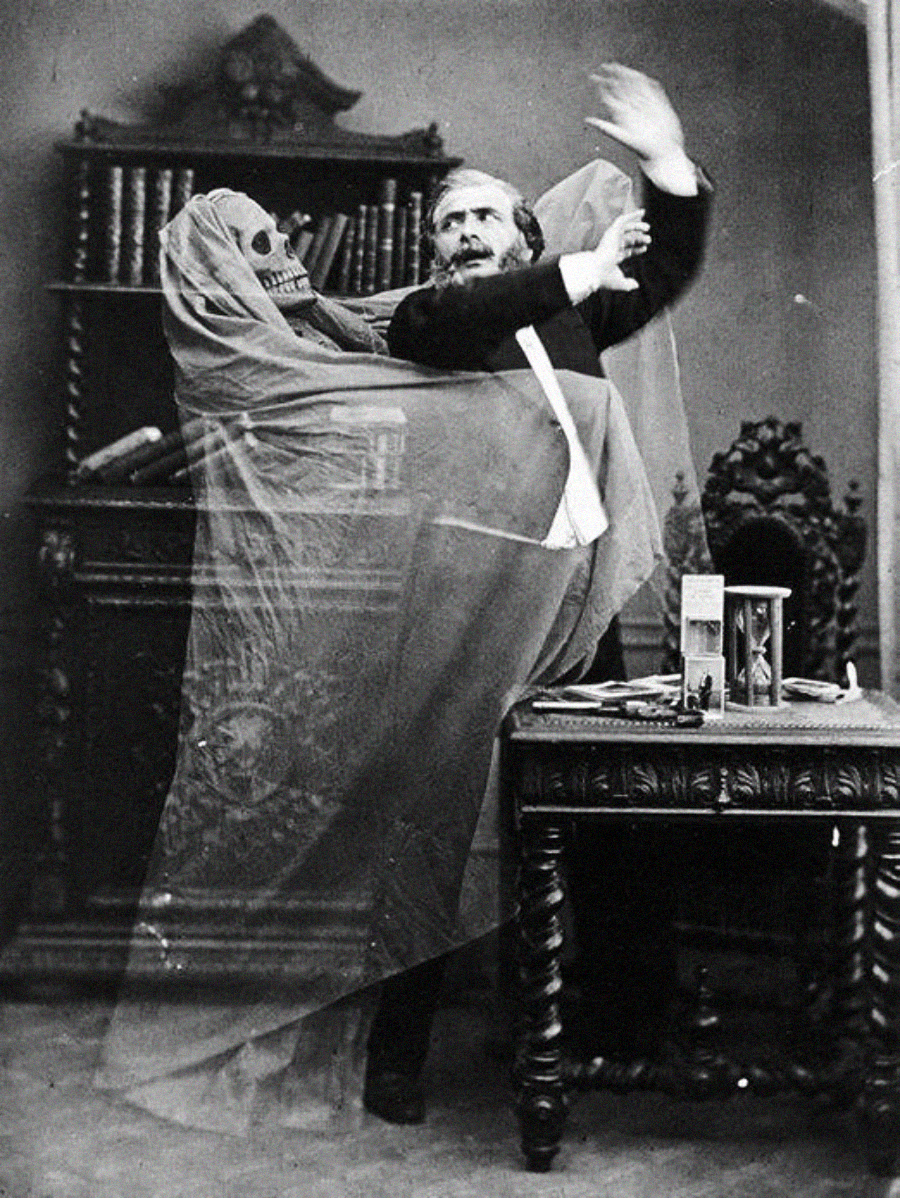 A man recoils in fear as a ghostly skeleton wrapped in a translucent veil looms behind him, arms raised. They stand beside an ornate table and bookshelf in a dark, dramatic setting.