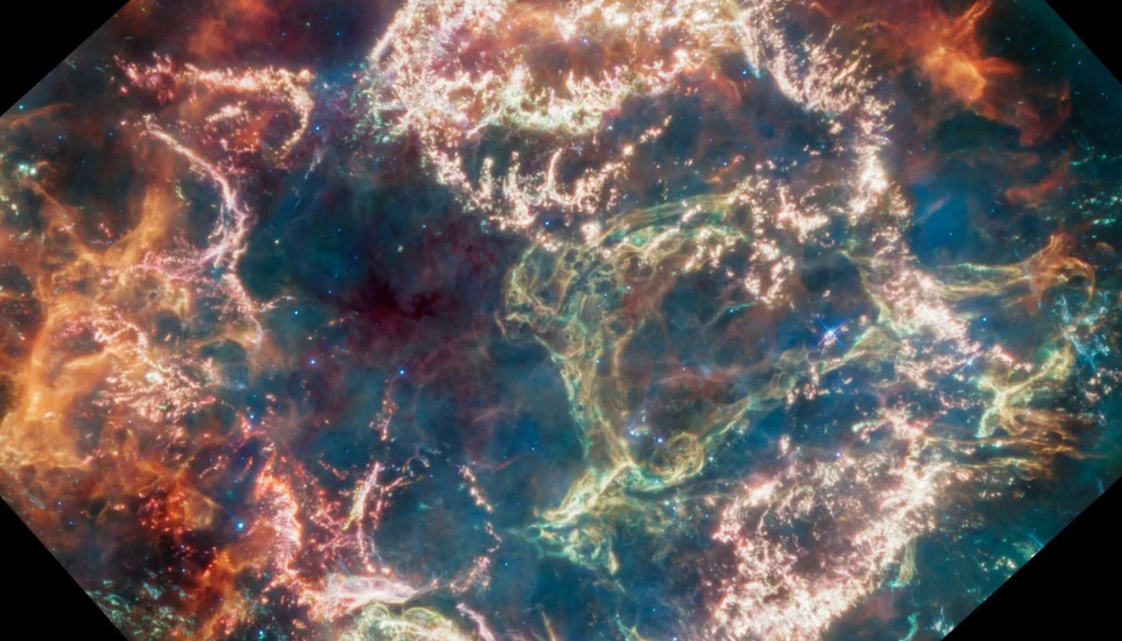 Colorful nebula with swirling clouds of blue, green, pink, and gold gas and dust, illuminated by glowing filaments against the dark background of space.
