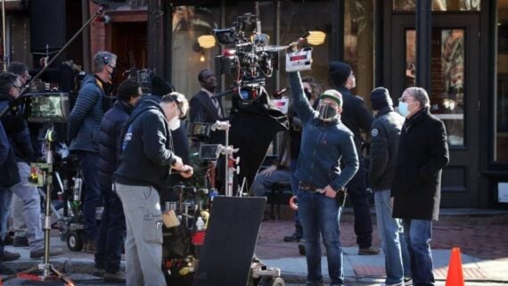 Film crew wearing masks and face shields operating cameras during an outdoor shoot