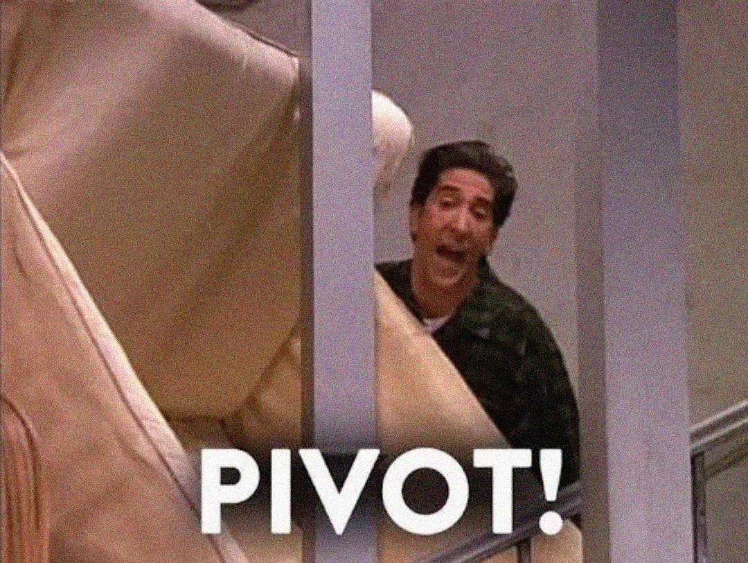 A man struggles to move a large beige couch up a staircase, yelling with effort. The word "PIVOT!" is written in bold white letters at the bottom of the image.
