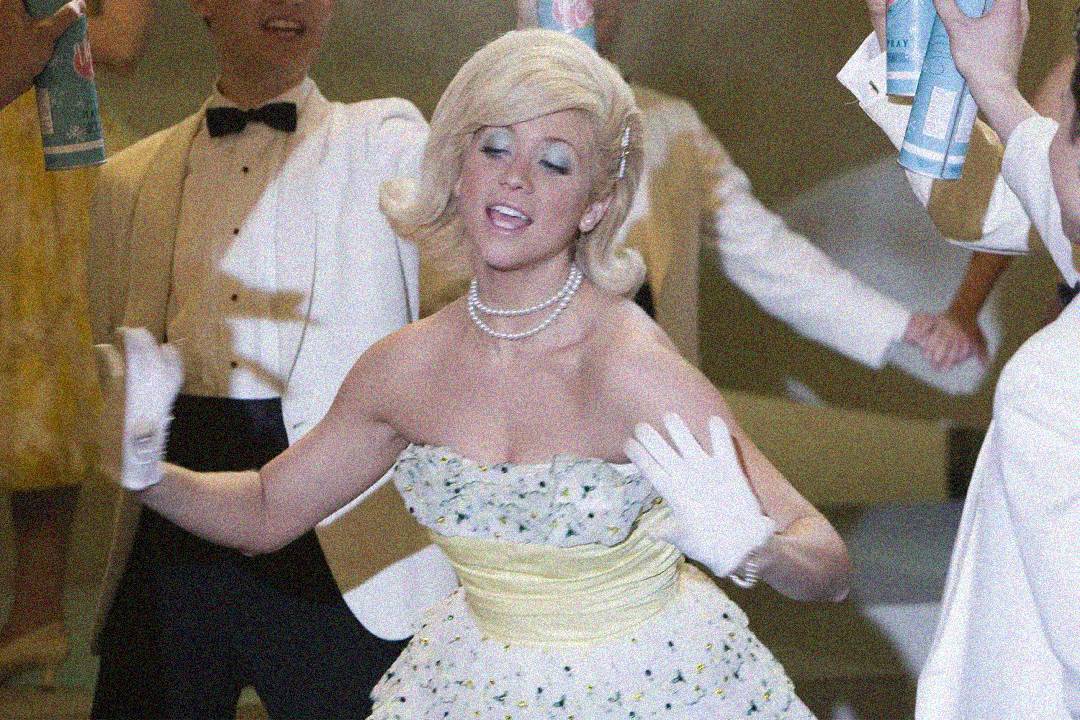 A woman in a vintage strapless dress with gloves and pearls dances with her eyes closed, surrounded by people in formal attire holding spray cans. The scene appears lively and retro.