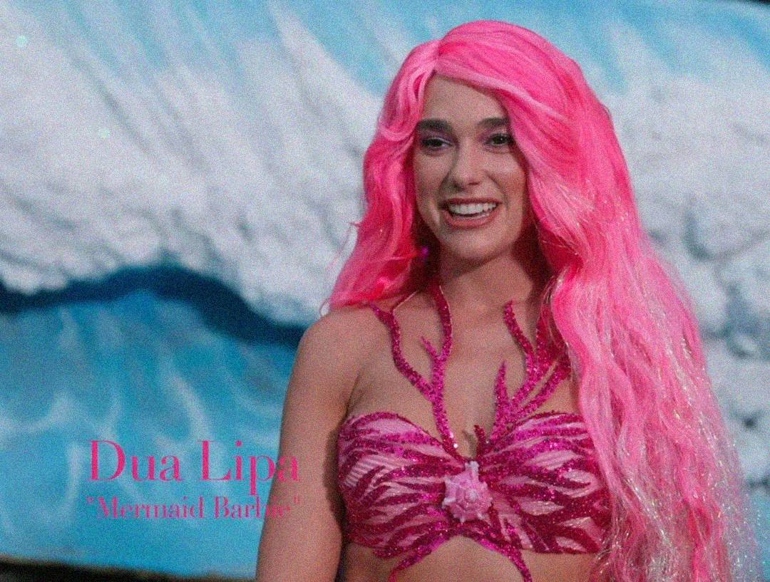 A woman with long, bright pink hair and a sparkling pink mermaid-inspired top smiles in front of a blue, wave-like background. Text on the image reads, "Dua Lipa 'Mermaid Barbie.'