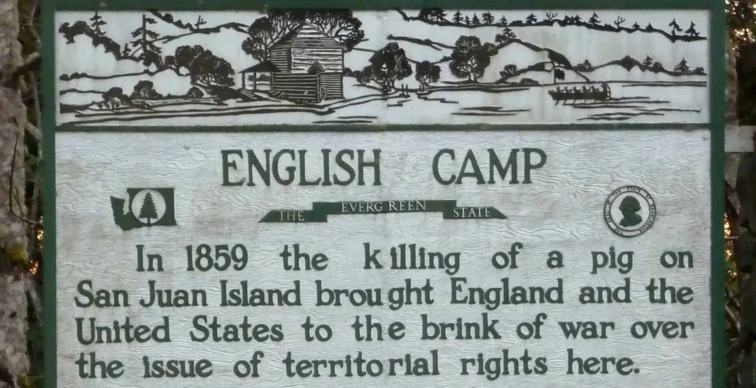 Historic sign reading: "ENGLISH CAMP. In 1859 the killing of a pig on San Juan Island brought England and the United States to the brink of war over the issue of territorial rights here." Includes an illustration of a cabin and landscape.