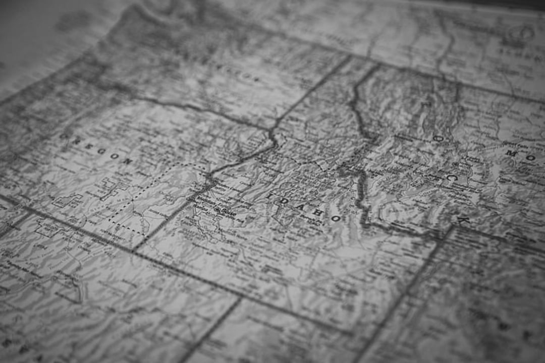 A black-and-white close-up image of a vintage map showing the northwestern United States, with states like Idaho and Montana visible, along with rivers and topographical details.