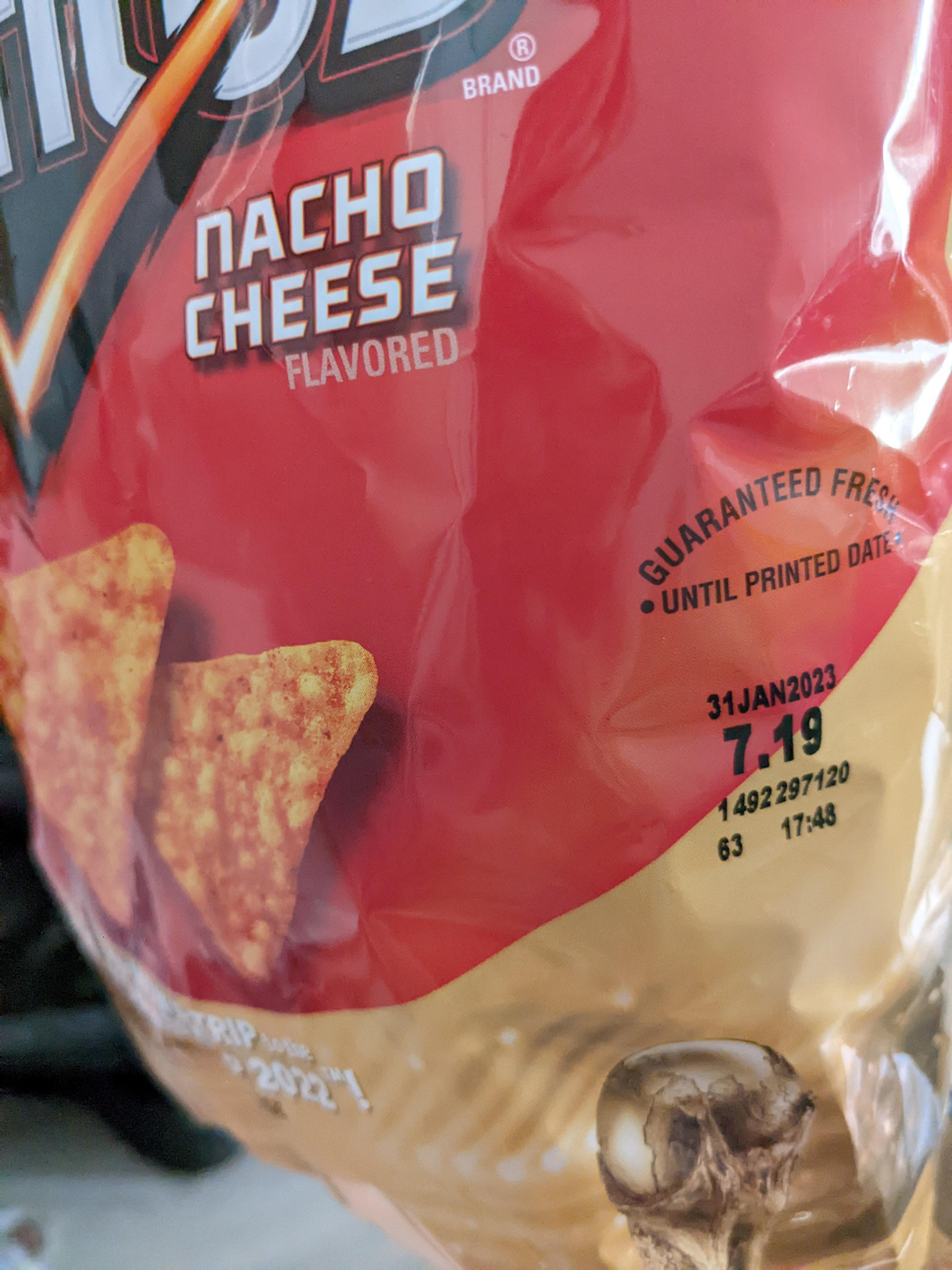 A close-up of a bag of Doritos Nacho Cheese chips showing the expiration date, "31JAN2023," and time "17:48," along with the phrase "GUARANTEED FRESH UNTIL PRINTED DATE.