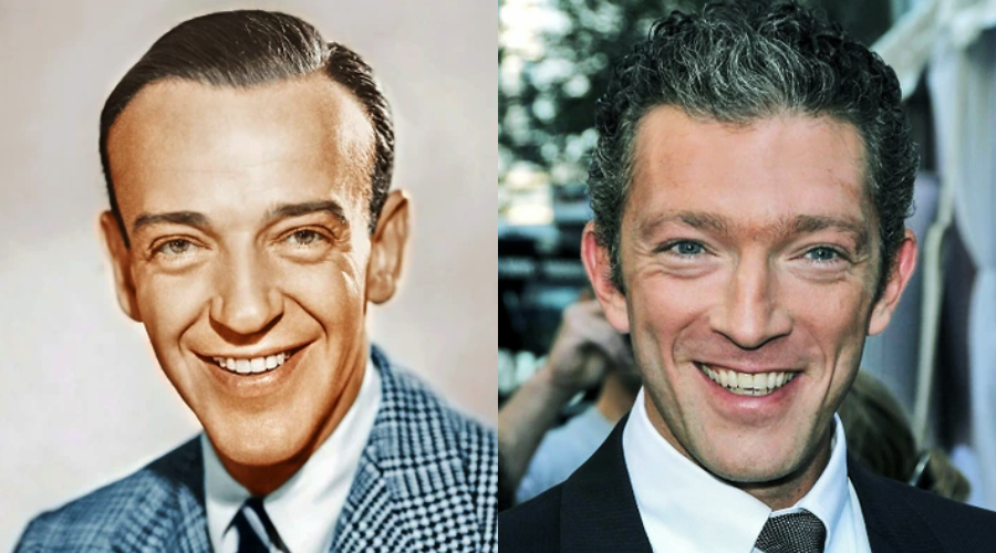 Two men are smiling at the camera; the man on the left has neatly combed dark hair and wears a checked jacket, while the man on the right has curly dark hair and wears a suit and tie.