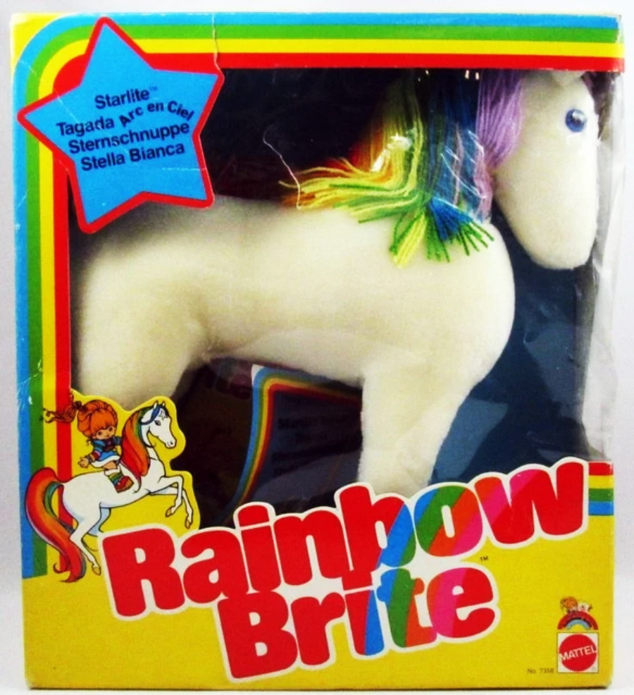 A plush Starlite horse toy with rainbow-colored mane and tail in original Rainbow Brite Mattel packaging, showing colorful branding and an illustration of Rainbow Brite riding Starlite.