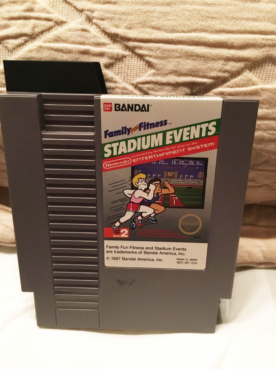A gray Nintendo Entertainment System game cartridge for "Stadium Events" by Bandai rests on a white surface, featuring a colorful label with runners on a track and a stadium in the background.