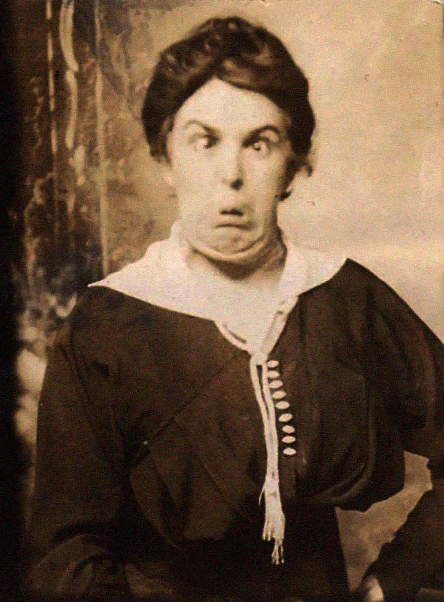 A vintage sepia-toned portrait of a woman in old-fashioned clothing making a silly, exaggerated facial expression with wide eyes and pursed lips.