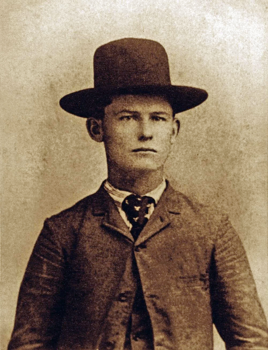Sepia-toned portrait of a young man wearing a suit, tie, and wide-brimmed hat, looking directly at the camera with a neutral expression.