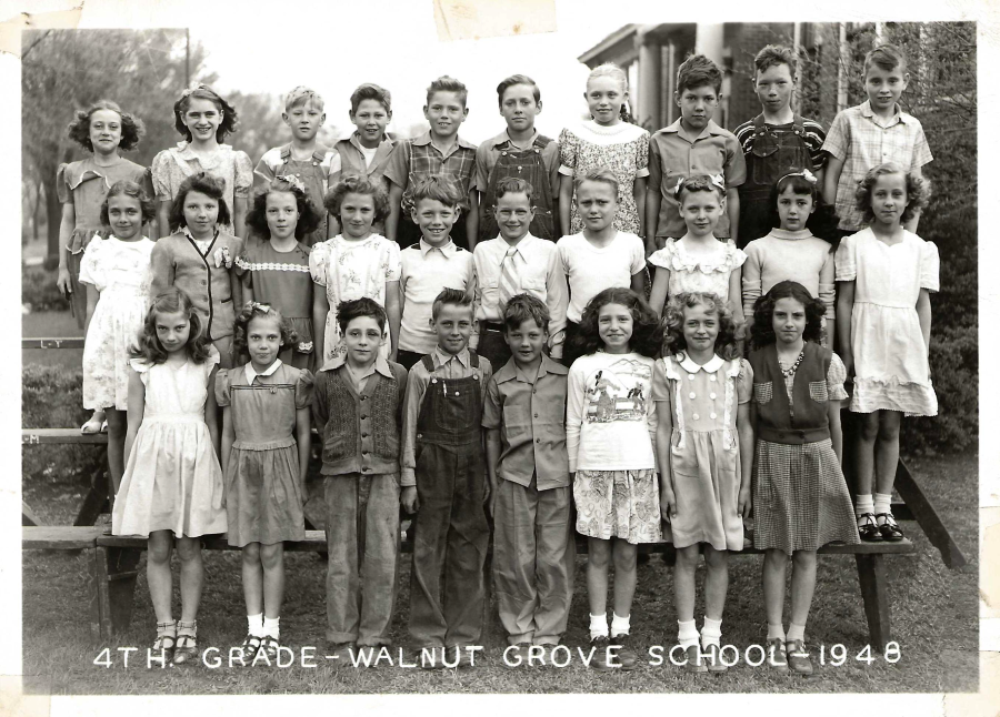 A black-and-white photo of a 4th grade class from Walnut Grove School in 1948, showing 29 children standing and sitting in four rows outside a school building, all facing the camera and dressed in 1940s attire.