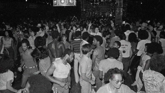 A lively crowd dancing together in a vibrant 80s nightclub