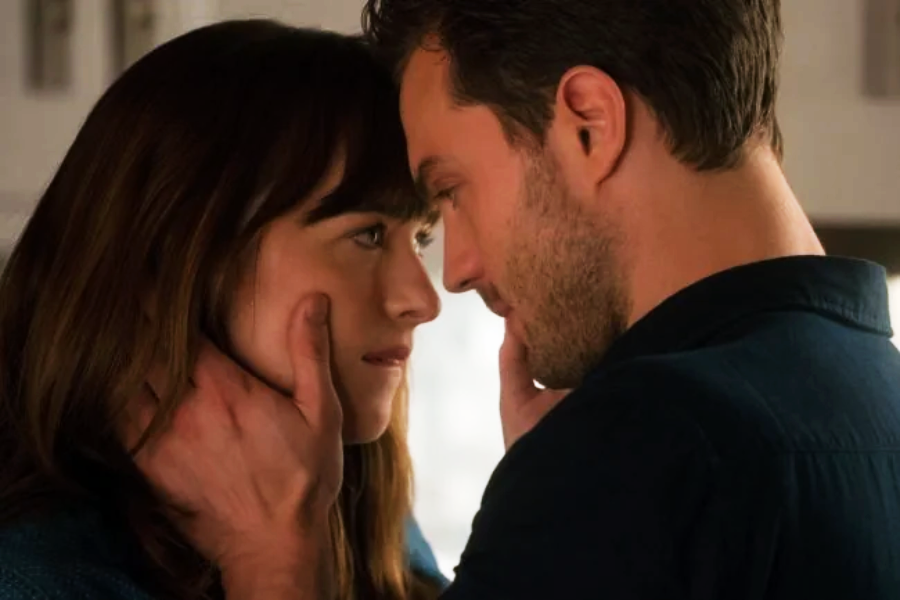 A man gently holds a woman's face as they look closely into each other's eyes, creating an intimate and romantic moment indoors.