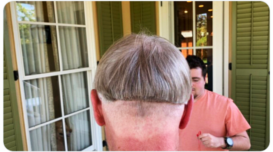 A person with short gray hair viewed from behind, showing a poorly done haircut with a straight, uneven line and shaved lower head. Another person in a peach shirt stands in front, holding scissors.