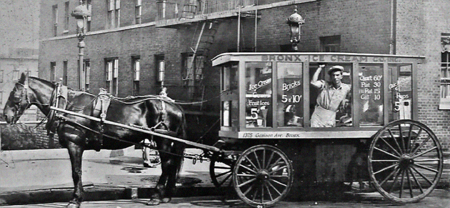 A vintage black-and-white photo shows a horse-drawn ice cream cart labeled “Bronx Ice Cream Co.” A man stands inside, serving from the window. Prices and menu items are written on the cart’s glass panels.
