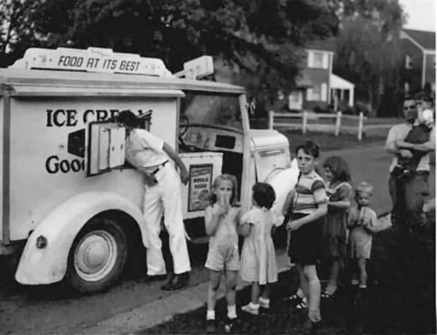 A group of children stand in line at an ice cream truck labeled "ICE CREAM Good," while the vendor serves from the window. An adult holds a baby nearby, and houses and trees are visible in the background.