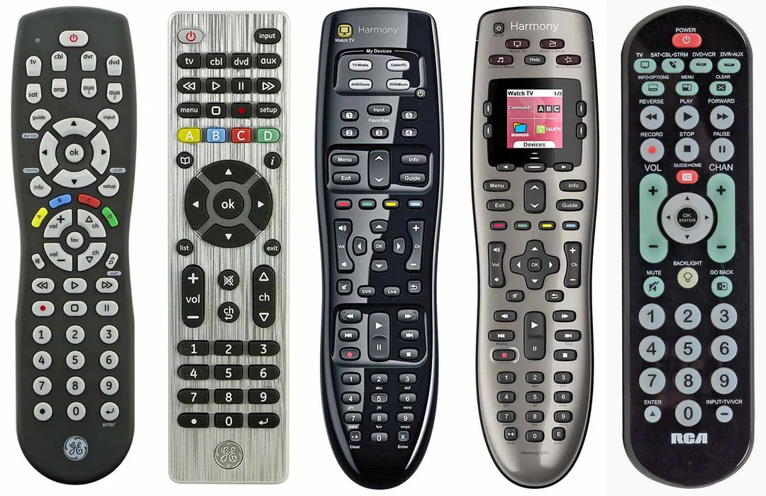 Five different universal TV remote controls are lined up side by side, each with various button layouts, colors, and designs. The remotes feature numerous buttons for functions like volume, channel, and media control.
