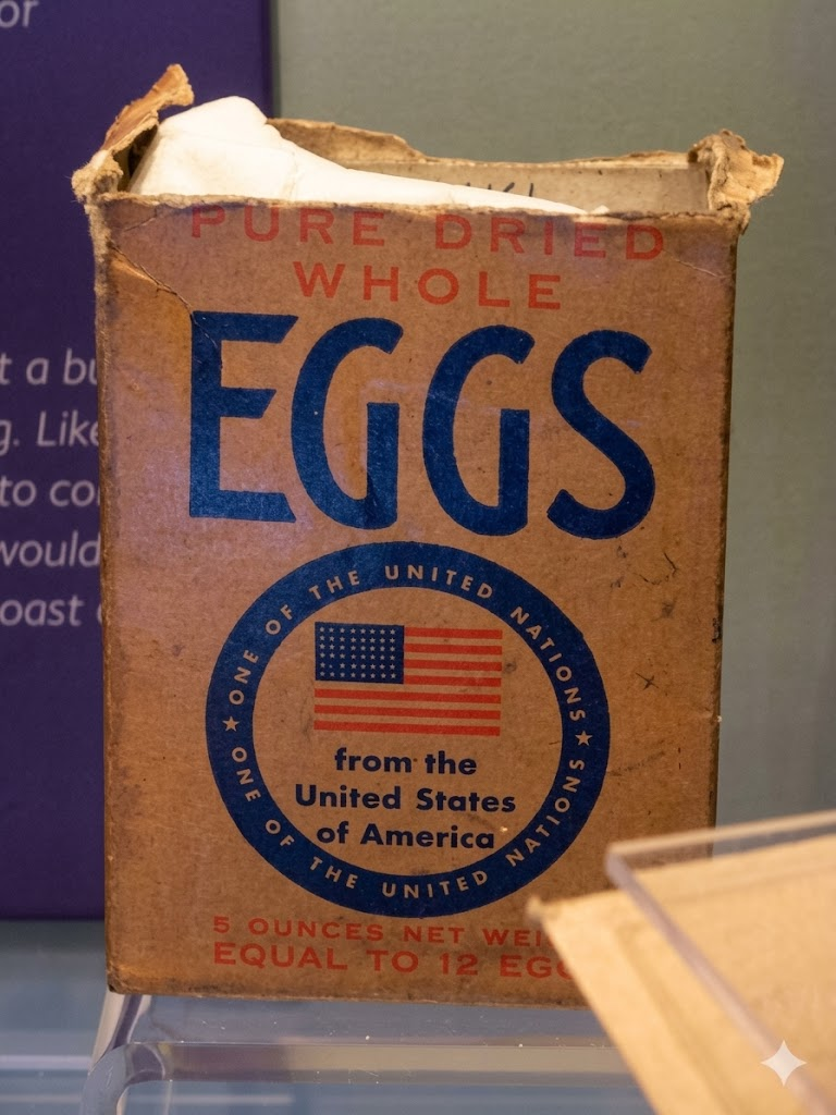 A vintage brown box labeled "Pure Dried Whole Eggs" with a U.S. flag and text stating "from the United States of America," and "5 ounces net weight, equal to 12 eggs." The box appears slightly worn.