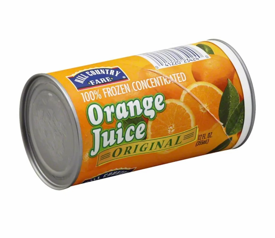 A can of Hill Country Fare 100% frozen concentrated orange juice, labeled "Original," with images of oranges and leaves on an orange background. The can size is 12 fl oz (355 mL).