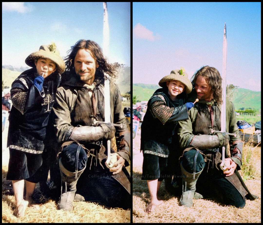 Two actors dressed in medieval costumes pose together outdoors on a film set. The adult kneels while the child in armor and a feathered hat stands beside him, both smiling against a sunny, scenic background.