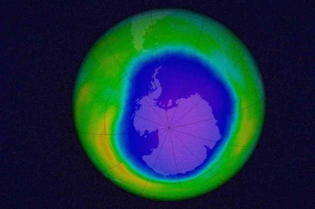 A satellite image of Earth’s South Pole showing Antarctica surrounded by a colored ring, representing the ozone hole with colors ranging from blue and purple to green and yellow.