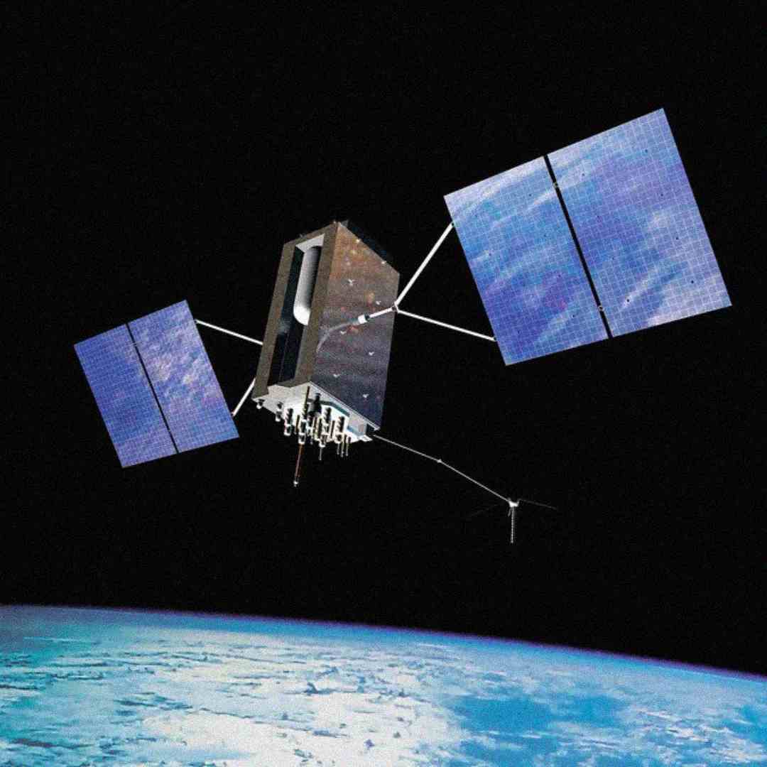 A satellite with large solar panels orbits above Earth, with the planet’s curved surface and blue atmosphere visible below against a black background of space.