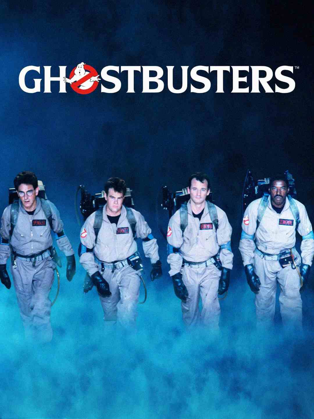 Four people in Ghostbusters uniforms walk forward through blue fog, wearing proton packs. The "Ghostbusters" logo and title appear above them against a dark background.