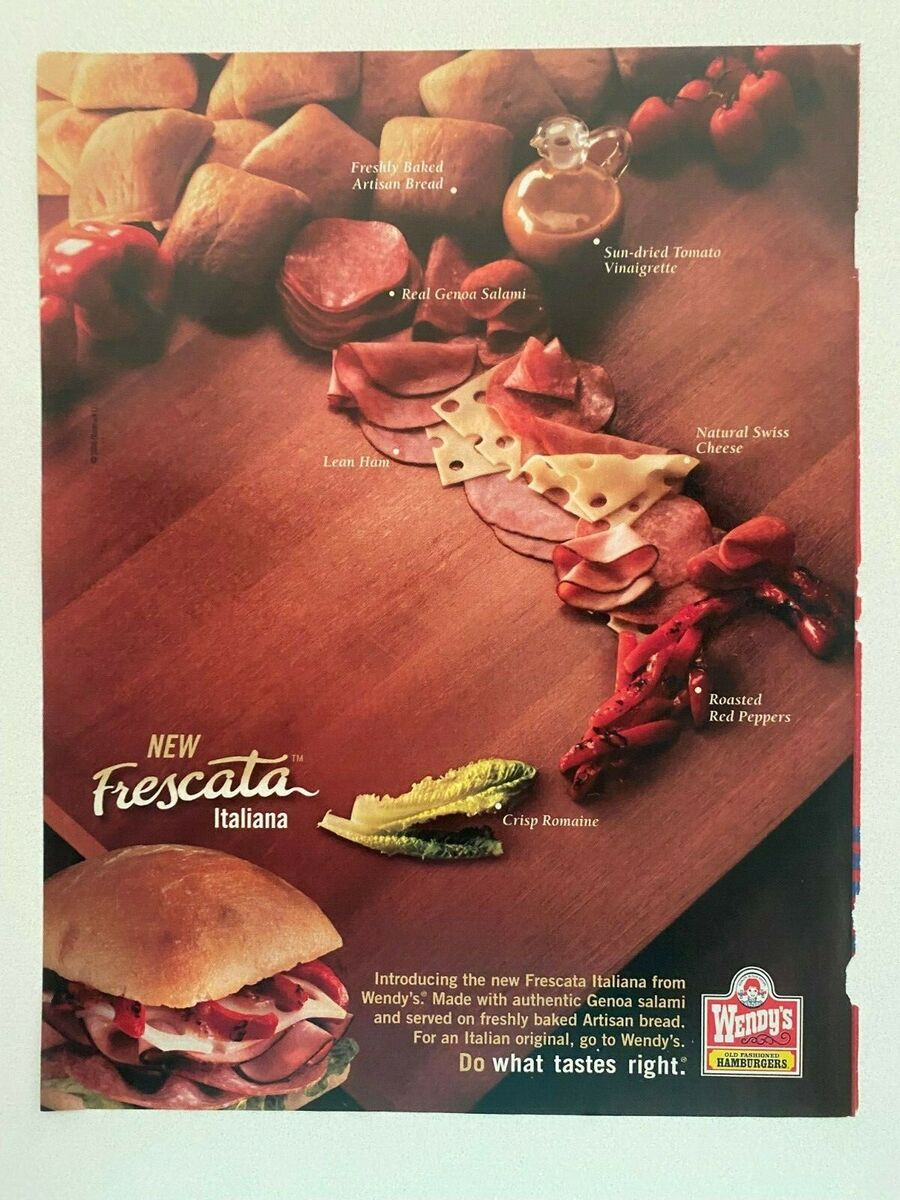 Wooden cutting board with artisan bread, Genoa salami, lean ham, Swiss cheese, vinaigrette, roasted red peppers, and romaine lettuce, with a Wendy’s Frescata Italiana sandwich at the bottom right and Wendy’s logo.