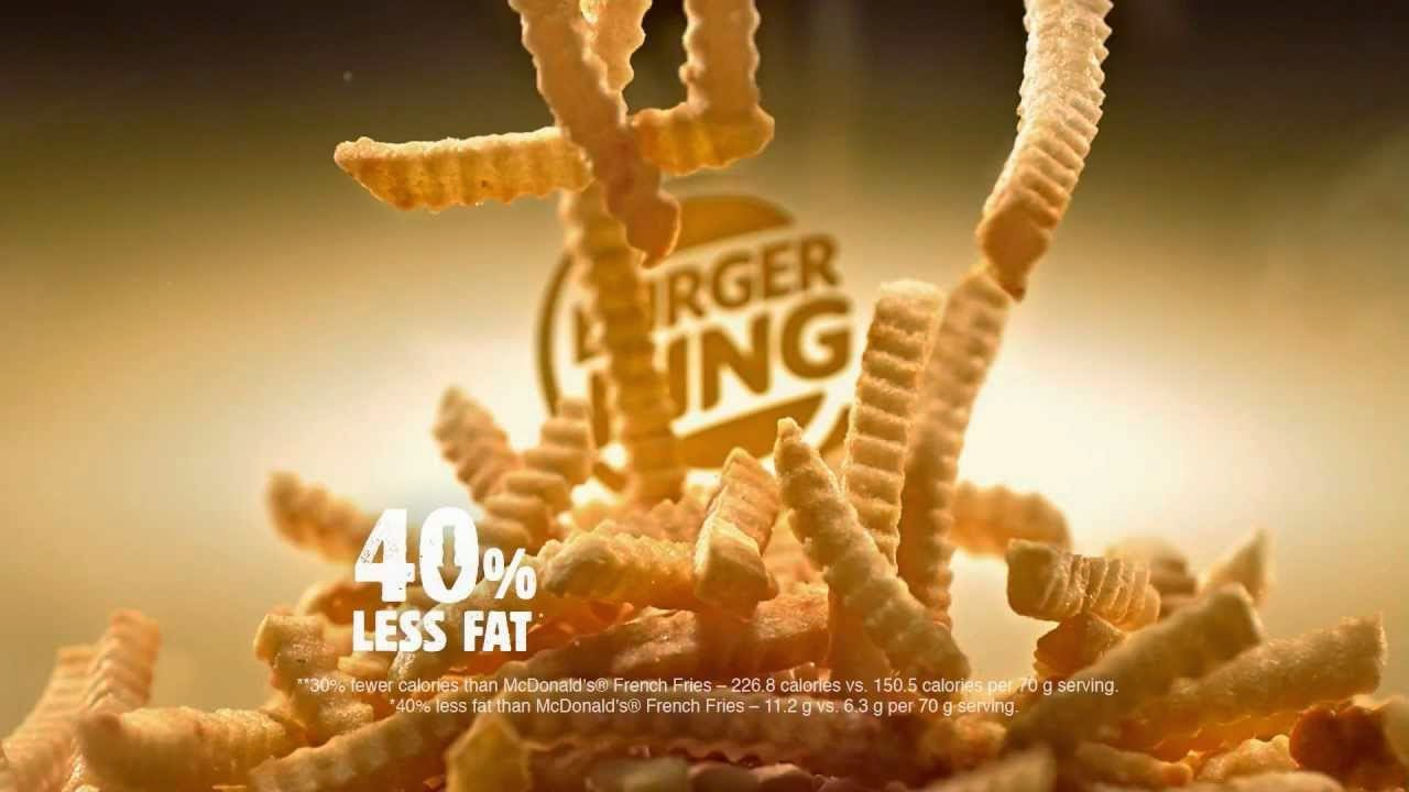 A pile of crinkle-cut French fries is shown with the Burger King logo in the background. White text in front reads “40% less fat,” promoting a healthier option for fries.