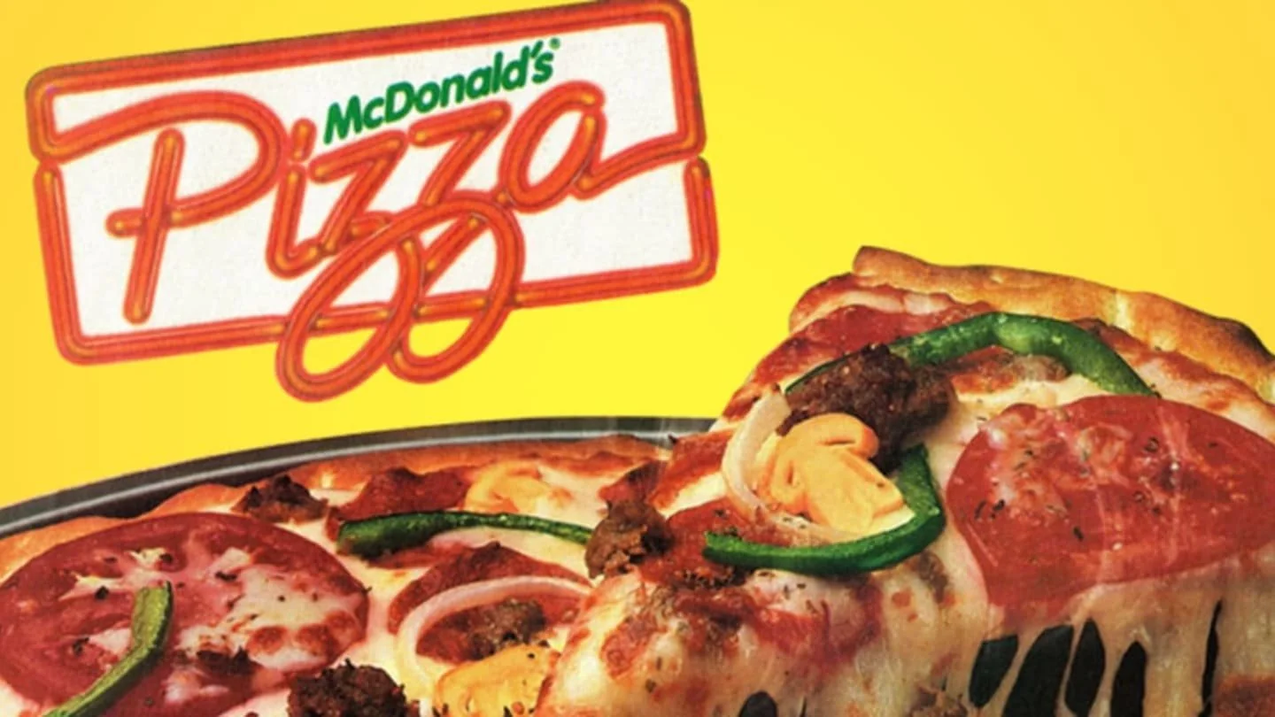 A close-up of a McDonald's pizza with pepperoni, onions, green peppers, and cheese, set against a bright yellow background with a retro McDonald's Pizza logo above it.