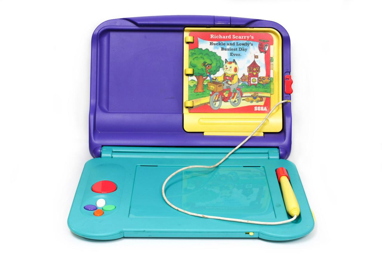 A colorful vintage electronic drawing toy with a purple and teal plastic case, featuring a Richard Scarry story screen, control buttons, a yellow pen connected by a cord, and a flat drawing area.