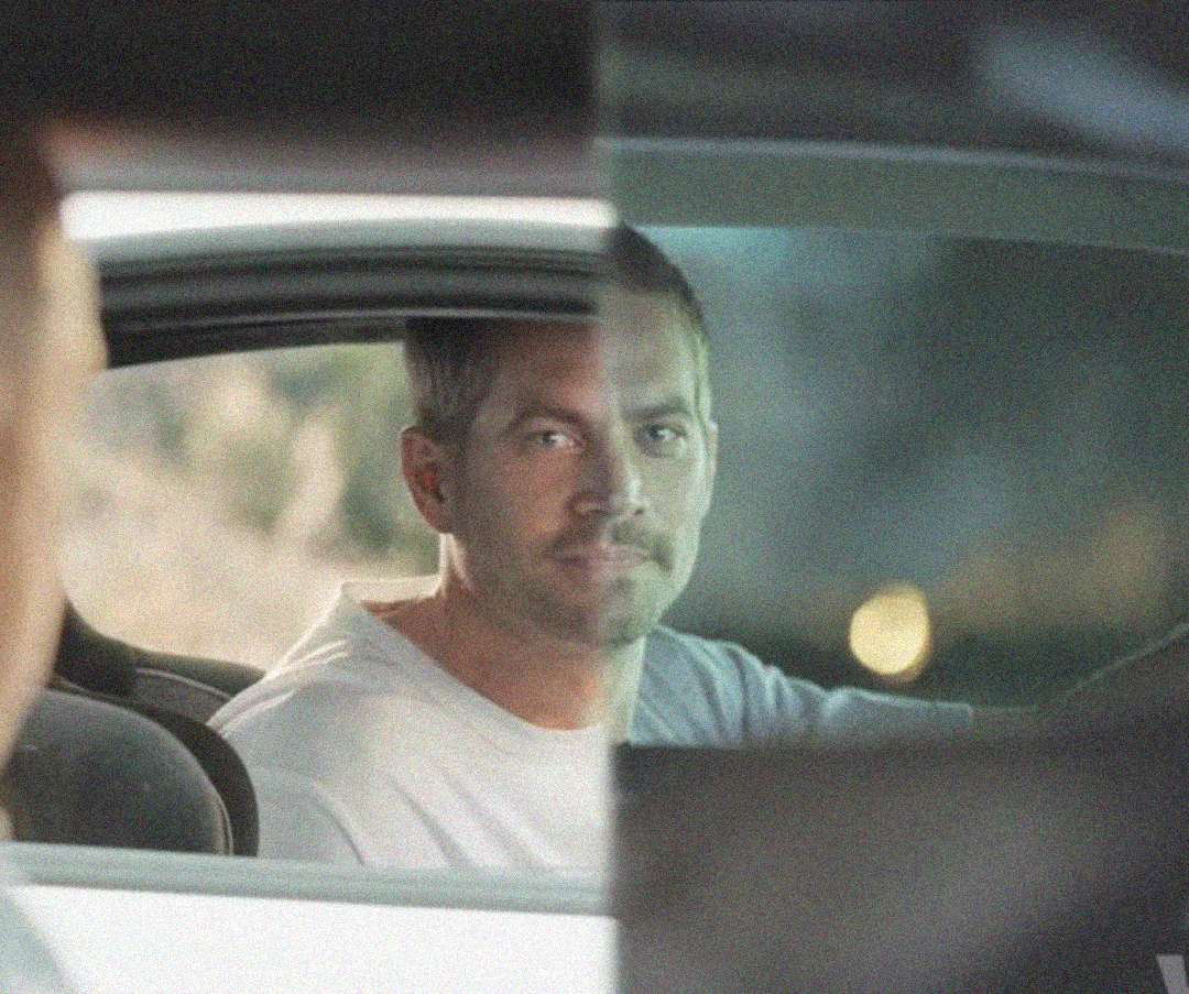 A man with short hair and a white shirt sits in the driver's seat of a car, looking ahead. The image is split vertically, showing two slightly different versions of him in the same position.