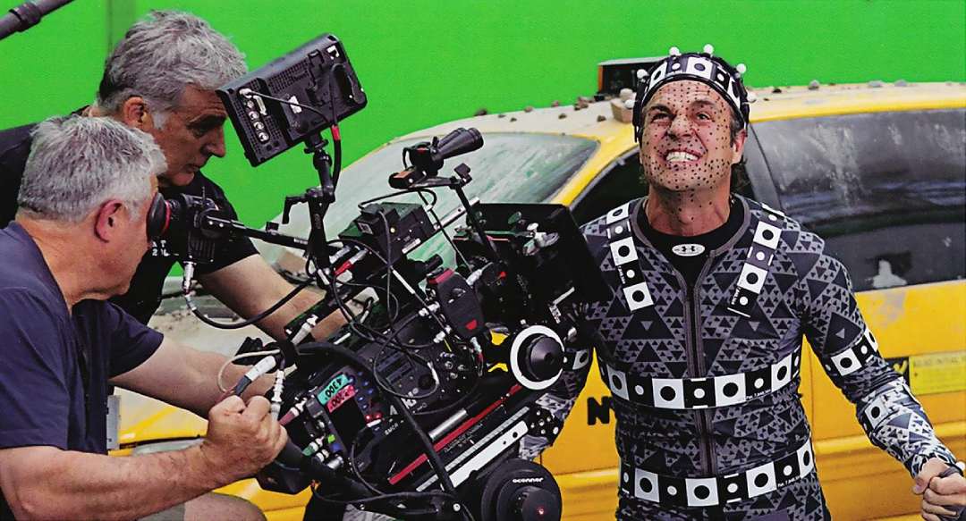 An actor in a motion capture suit with facial markers performs in front of a green screen and a yellow taxi as a film crew records with a camera.
