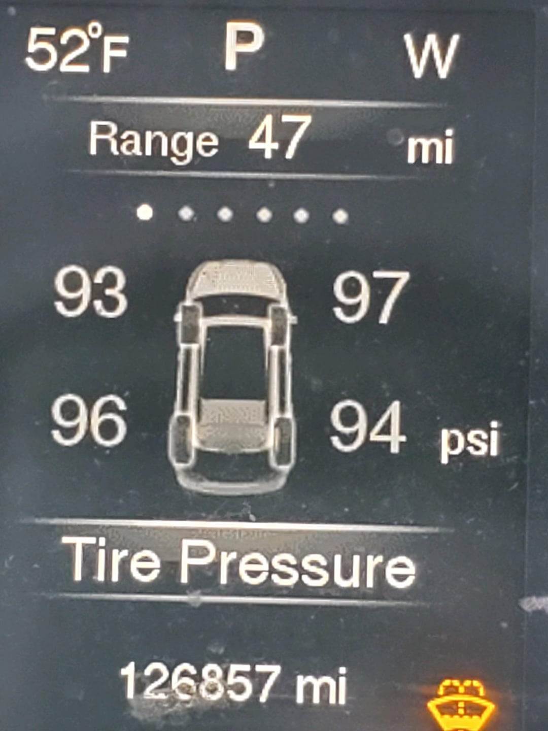 Car dashboard display showing outside temperature 52°F, gear in Park, direction West, range 47 miles. Tire pressures: front left 93 psi, front right 97 psi, rear left 96 psi, rear right 94 psi. Odometer: 126,857 miles. Warning light on.