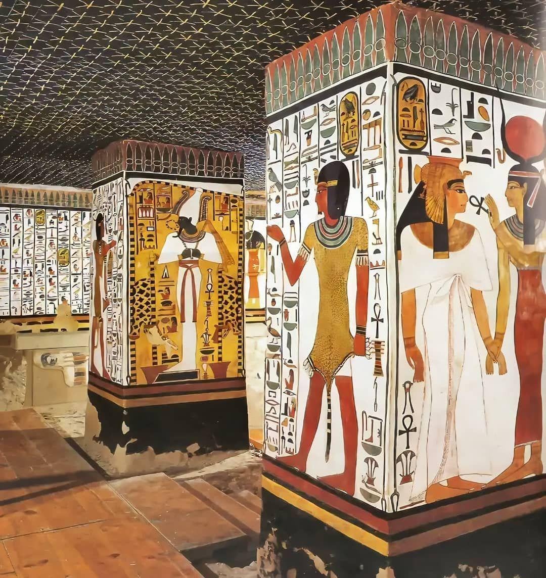 Ancient Egyptian tomb interior with columns and walls covered in colorful hieroglyphs and detailed paintings of figures in traditional Egyptian attire. The ceiling is dark and decorated with yellow star patterns.