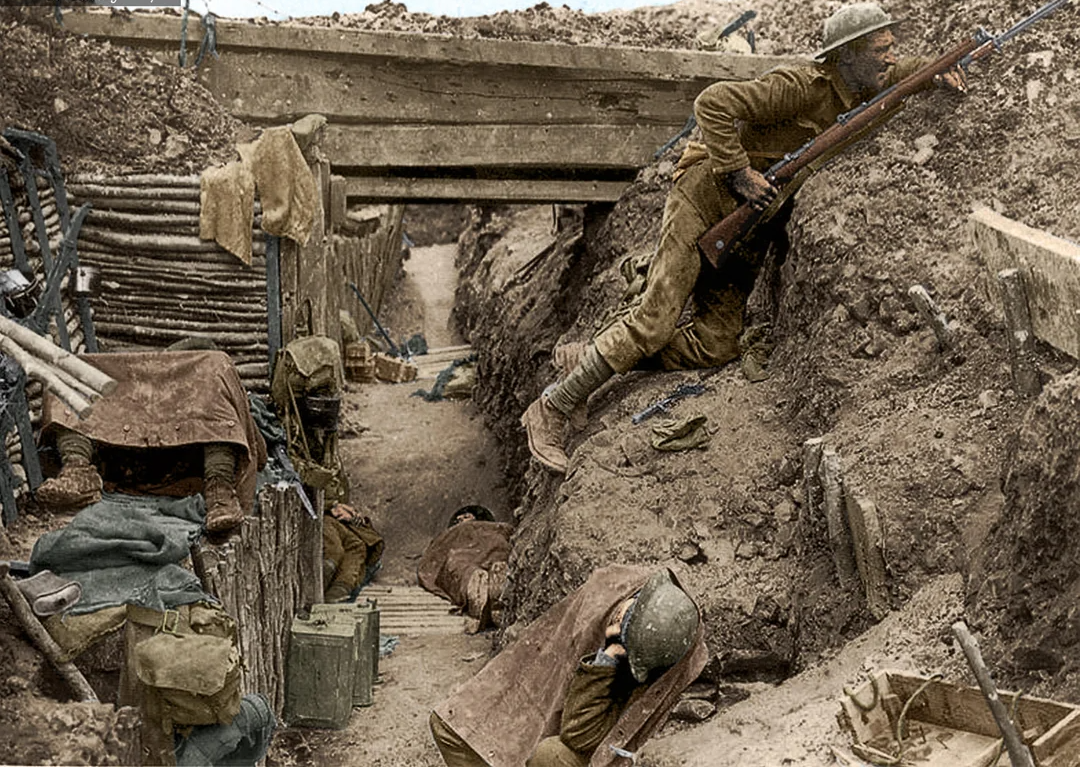World War I soldiers in a muddy trench; one climbs out holding a rifle while others lie motionless on the ground. Sandbags, wooden planks, and equipment line the narrow, dirt trench under a wooden bridge.
