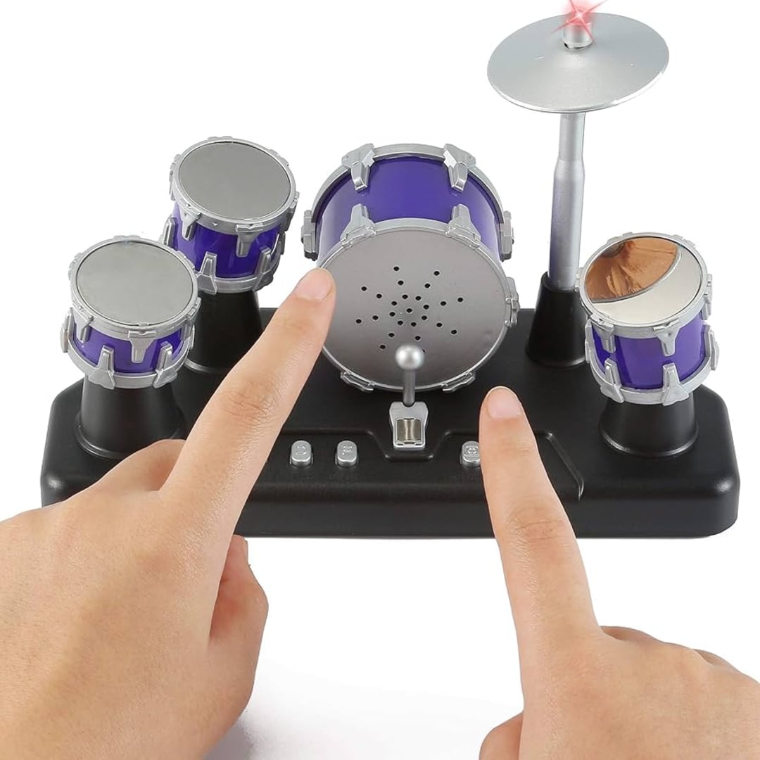 A person's hands playing a miniature toy drum set with purple drums and a silver cymbal on a black base.