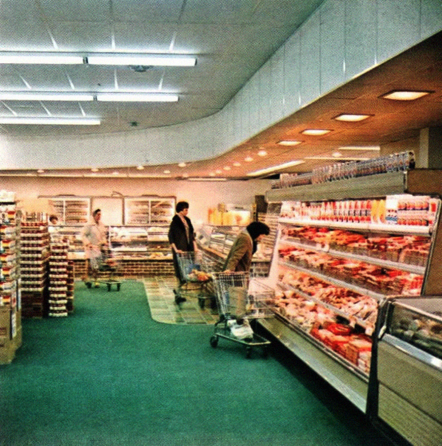 A retro supermarket scene with shoppers browsing refrigerated cases filled with food. The store has green carpeting, bright overhead lights, and shelves stocked with various grocery items.