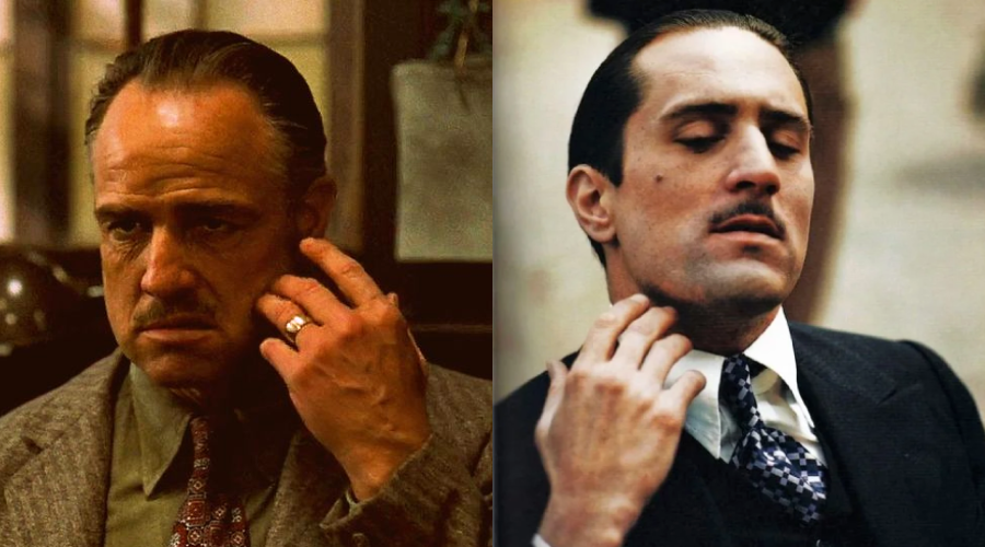 Side-by-side images of two men in suits, both touching the side of their faces with their right hands. The man on the left is older with slicked-back hair; the man on the right is younger with a thin mustache.