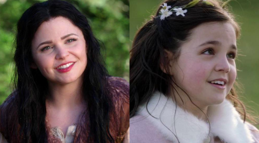 Two females shown side by side outdoors; the left is an adult woman with long dark hair, smiling and wearing a fur-trimmed outfit, and the right is a young girl with dark hair and white flowers, also smiling.