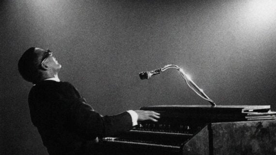 Ray Charles smiling while playing the piano during a live performance.