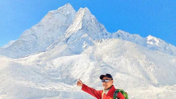 Snow-covered Mount Everest glowing at sunrise with climbers ascending the dangerous ridge.
