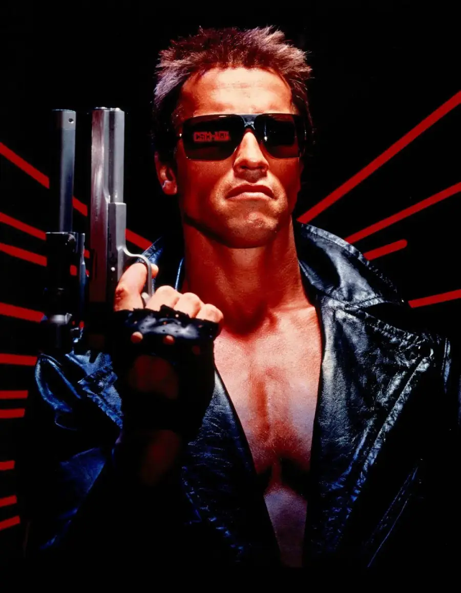 A muscular man wearing dark sunglasses and a black leather jacket holds up a large handgun. Red laser-like lines radiate behind him against a dark background.