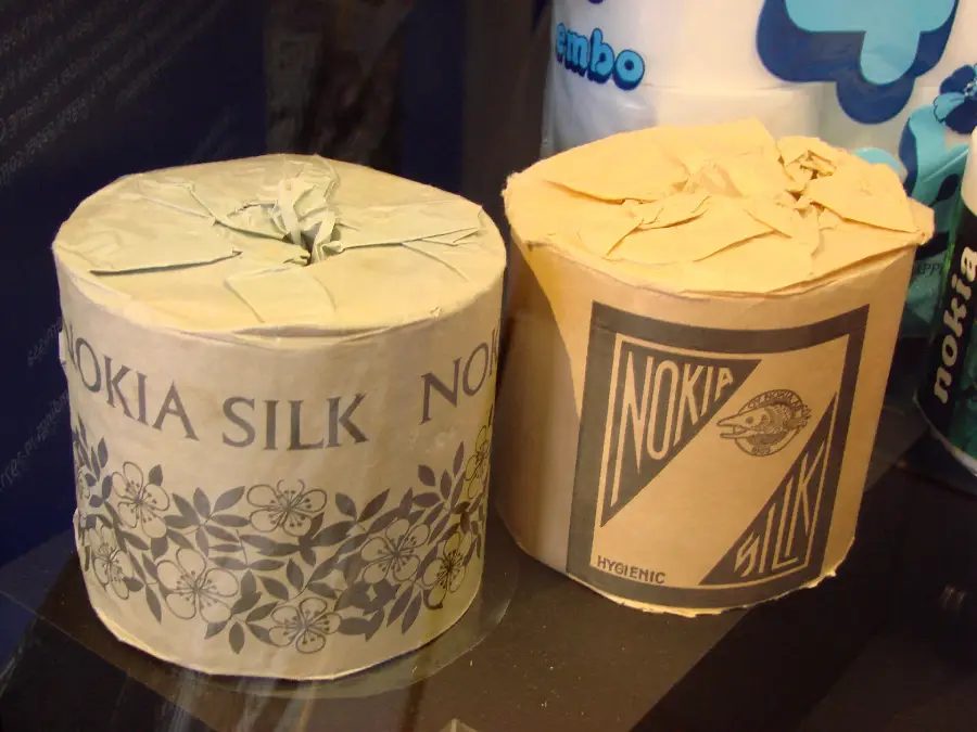 Two rolls of vintage toilet paper labeled "Nokia Silk," each with patterned packaging, are displayed side by side. One has a floral design and the other a geometric label with a fish graphic.