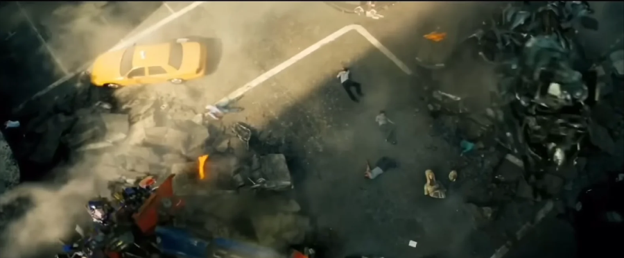 A yellow taxi and several people lie scattered on a damaged city street surrounded by debris, with smoke and dust rising, suggesting recent destruction.