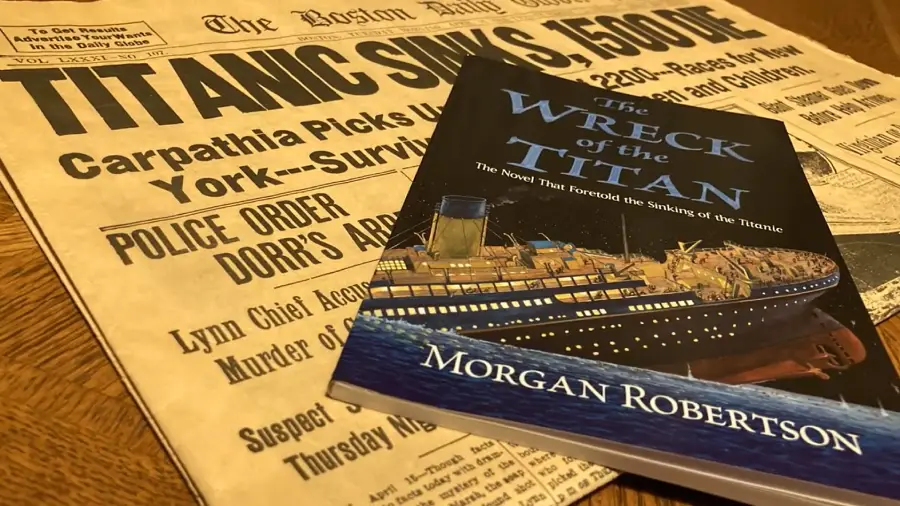 A vintage newspaper with the headline “TITANIC SINKS, 1,500 DIE” lies on a table beneath a book titled "The Wreck of the Titan" by Morgan Robertson, featuring an illustration of a large ship sinking.